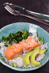 Salmon with spinach and avocado. Fish with rice and sesame seeds