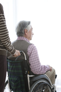 Senior woman pushing her husband in wheelchair