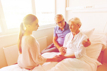 family visiting ill senior woman at hospital