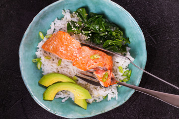 Salmon with spinach and avocado. Fish with rice and sesame seeds. View from above, top studio shot
