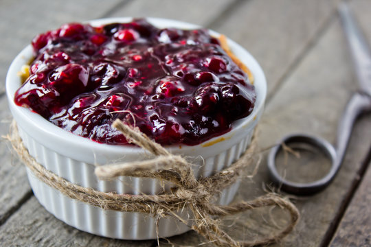 cheesecake in white ramekin with a string , rustic ddecoration, wild fruit in gel on top