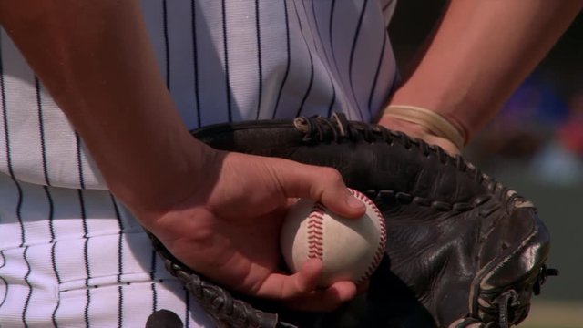 Close-up of left-handed pitcher holding ball behind his back, zoom-out to wind-up