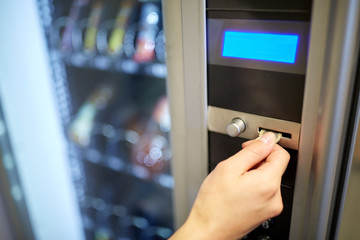 hand inserting euro coin to vending machine slot