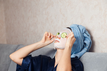 The girl puts and corrects a nutritious mask on a skin with green ripe fresh cucumber. Mask for...