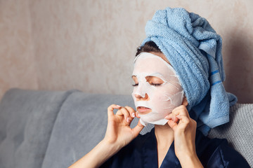 Girl puts a nourishing mask on the skin. Mask for rejuvenating and eliminating skin defects. Acne,...