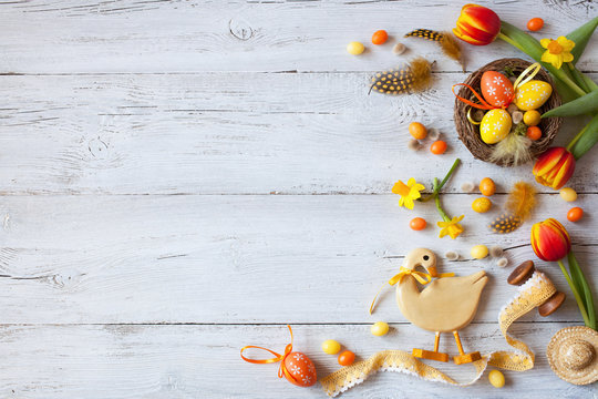 Easter wooden background with eggs, candy and flowers