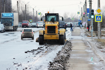 tractor cleans the road in the city of dirty snow