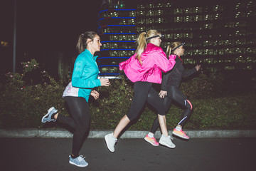Three women running in the night in the city center