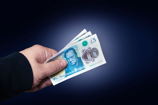 Money English five pound note in a man's hand concept.