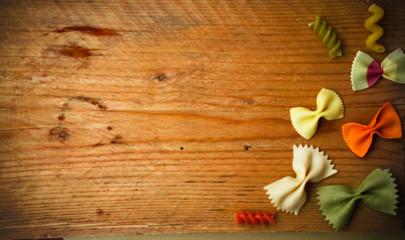 Obraz na płótnie Canvas colored dry pasta flavors on the rustic wooden table. Creative food background.Italian food,top view with place for text