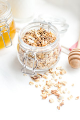 Top view breakfast of homemade granola cereal with nuts and fruit, honey with drizzlier on white background. Healthy food, Diet, Detox, Clean Eating, Vegetarian concept.