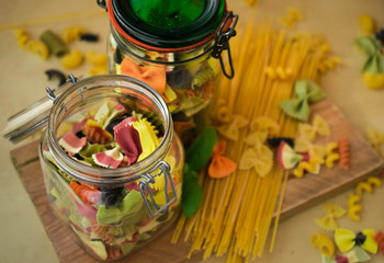 Mixed colorfull pasta selection, in the glass jar Italian food background,