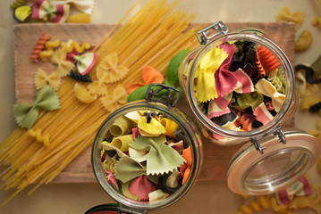 Mixed dried colorfull pasta selection, in the glass jar Italian food background,