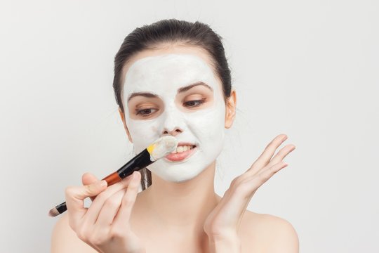 Woman with a sponge in her hands and cream on her face, cotton pads, clean face