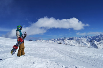 snowboarder standing with snowboard in the mountains.