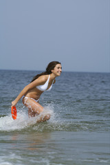 Young brunette woman in the sea holding a Frisbee, selective focus