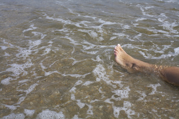Obraz premium Naked leg of a young woman in the shallow water of the sea, high angle view