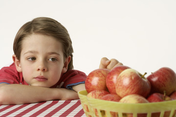Fototapeta premium Boy sitting beside a few apples