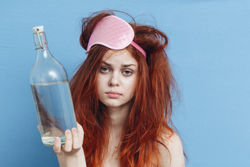 Woman with a bottle of alcohol, the morning after a party, a hangover