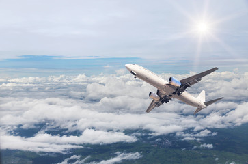 airplane flying away in to sky high altitude above the white clouds with sunlight