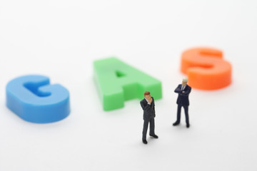 Two businessmen figurines standing next to the word Gas