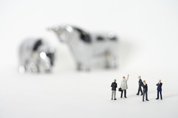 Group of businessmen figurines standing in front of bull and bear