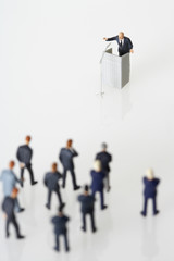 Group of businessmen figurines listening a speech