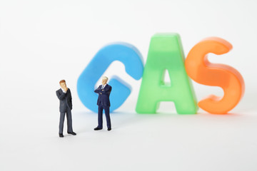 Two businessmen figurines in front of the word Gas