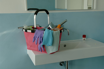 Fototapeta na wymiar Bucket with cleaning utensils on the brim of a washbasin