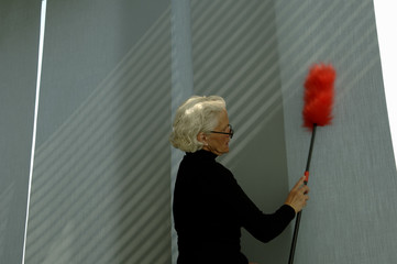Senior woman cleaning the wall with a feather duster