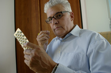 Senior man about to take a pill from a package, close-up