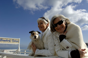 Portrait of two mature women with a dog at the Baltic Sea