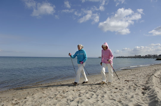 Two mature women Nordic walking at Baltic Sea beach