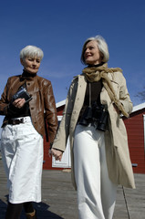 Fototapeta premium Two mature women holding hands and walking