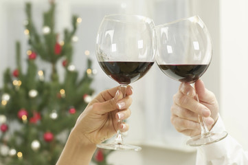 Two people chinking glasses with red wine