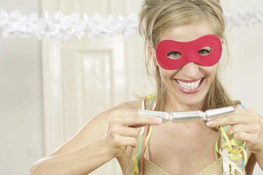 Woman with mask pulling on a Christmas cracker