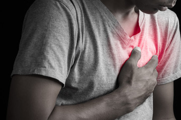 Man clutching his chest from acute pain heart attack symptom.