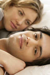 Obraz premium Young couple lying in a bed, man looking at camera