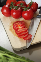 Tomatoes on a carving board next to a kitchen knife, high angle view