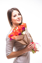 Beautiful girl in the grey dress with flowers tulips in hands on a light background