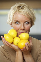 Mature woman holding a medium group of lemons in her hands, close-up