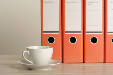 Cup of coffee in front of folders