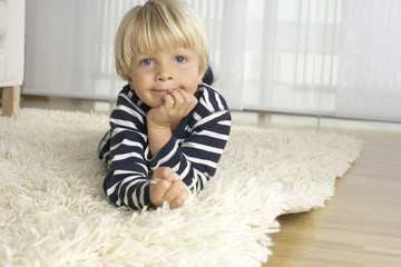 Boy (4-5 Years) lying on a carpet and looking at camera