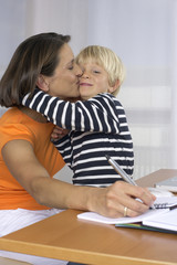 Mother taking notes while kissing her son (4-5 Years)