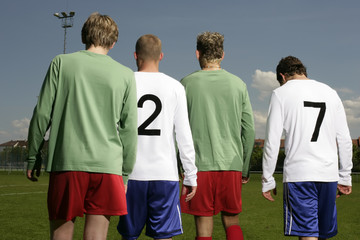 Four footballers of adverse teams standing next to each other, rear view