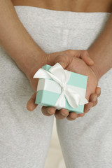 Man holding a present behind his back, focus on hands