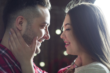 Young future parents on the background of bright lights of garlands.