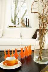 Vase with branches next to a the silhouette of Easter bunnies in a living room, selective focus