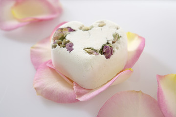A heart-shaped piece of soap on rose petals