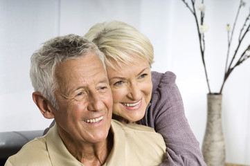 Senior woman embracing man form behind